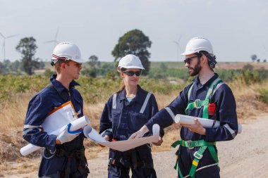 Ekip mühendisi rüzgar türbini işçi üniforması güvenlik anketi operasyon planlama yel değirmeni temiz enerjisini tartışıyor. Alternatif teknoloji çevreyi korur küresel ısınma sorunlarını azaltır.