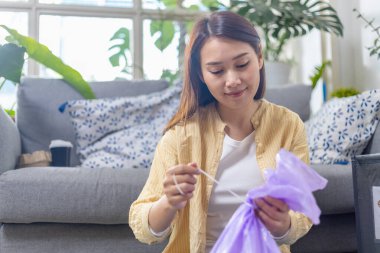 Evde oturan genç bir kadın kağıt ve plastik atıkları ayırıyor. Geri dönüşüm için çöp ayıklama. Küresel ısınmanın azaltılması. Çevre koruma kavramı.