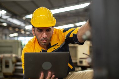 Endüstriyel mühendis üniforma ve kask giyer dizüstü bilgisayar kullanır fabrikada sistem makinesini kontrol ederler. Teknik direktör imalatı. İşçi sanayi fabrikası.