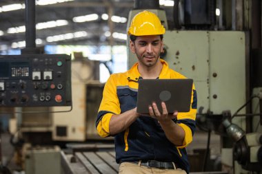 Endüstriyel mühendis üniforma ve kask giyer dizüstü bilgisayar kullanır fabrikada sistem makinesini kontrol ederler. Teknik direktör imalatı. İşçi sanayi fabrikası.