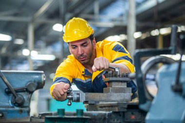 Kafkasyalı mühendis işçiler fabrika endüstrisinde çalışan sarı sapkalı torna makineleri giyerler. Mekanik operatör erkek işçi. Ağır sanayi konsepti.