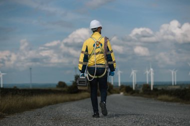 Rüzgâr türbininde çalışan insan mühendislerinin alet çantası ve iple bakımı için geri bakış açısı. Yenilenebilir enerji rüzgar türbini. Teknoloji çevreyi koruyor küresel ısınma sorunlarını azaltıyor.