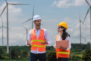 Team engineer wearing safety uniform holding laptop discussed plan about renewable energy at station energy power wind. technology protect environment reduce global warming problems.