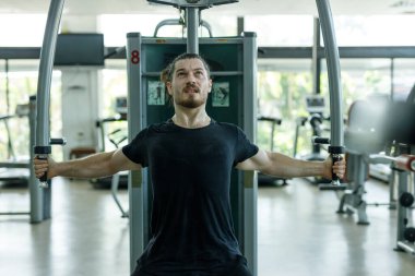 Spor salonundaki kalorili pres makinesinde çalışan adam sağlık için kilo kaybediyor. Spor salonunda göğüs pres makinesi çalıştıran güçlü bir sporcu. Kol ve omuz kaslarını geliştirmek için egzersiz..