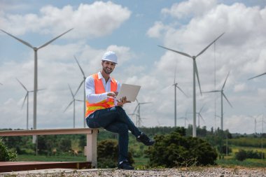 Dizüstü bilgisayarı tutan güvenlik üniforması giyen mühendis istasyon enerji rüzgârında yenilenebilir enerji ile ilgili planı tartıştı. teknoloji çevreyi korur küresel ısınma sorunlarını azaltır.