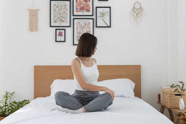 Азиатская молодая женщина утренние упражнения после пробуждения на кровати, растянуть ноги вперед. Расслабьтесь и потренируйтесь дома в отпуске. Активность движения тела.