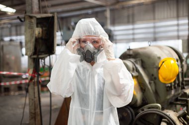 Koruyucu maske takan kadın kimya müfettişi ve tehlikeli madde giysisi endüstriyel kimyayı inceliyor. İnsan vücudu ve çevresi için zararlı maddelerin analizi.