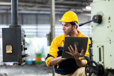 Endüstriyel mühendis üniforma ve kask giyer dizüstü bilgisayar kullanır fabrikada sistem makinesini kontrol ederler. Teknik direktör imalatı. İşçi sanayi fabrikası.