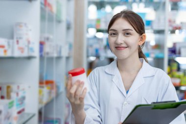 Kadın eczacılar eczanedeki hasta panoları için ilaç seçiyorlar. Elinde pano ilacı tutan uyuşturucu satıcısı. Hastaya göndermeden önce bilgi için şişe seçiniz..