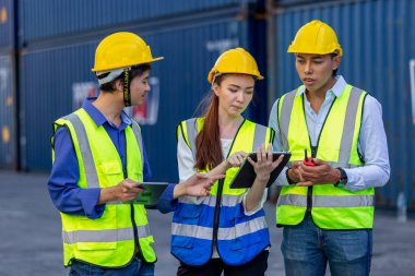 Ekip teknisyeni, ustabaşı ve ortağı kargo konteynır bölgesinde güvenlik kaskı takıyor, işçi başarısı, konteynır geçmişi