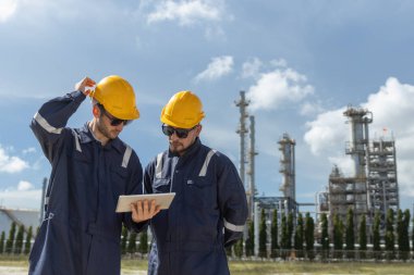 Profesyonel elektrik mühendisi üniforması. Petrol petrokimyasını rafine etmek için birlikte çalışıyorlar. Tablet kullanıyorlar. Endüstriyel fabrika alan kontrol enerji santrali.