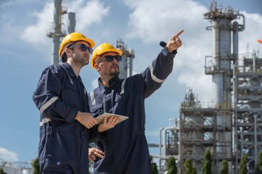 Profesyonel elektrik mühendisi üniforması. Petrol petrokimyasını rafine etmek için birlikte çalışıyorlar. Tablet kullanıyorlar. Endüstriyel fabrika alan kontrol enerji santrali.