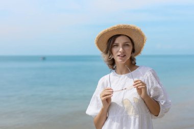 Güzel, kendine güvenen, çekici, çekici, sarı saçlı bir kadın. Kenarlı bir şapka takıyor ve tropikal sahilde eğleniyor. Portre kadın rahatlaması tatilin tadını çıkarıyor. Moda hanımefendisi yaz yaşam tarzı.