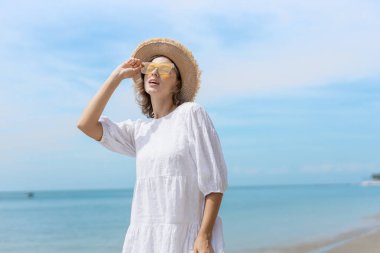 Güzel, kendine güvenen, çekici, çekici, sarı saçlı bir kadın. Kenarlı bir şapka takıyor ve tropikal sahilde eğleniyor. Portre kadın rahatlaması tatilin tadını çıkarıyor. Moda hanımefendisi yaz yaşam tarzı.
