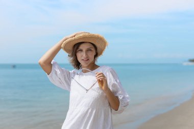 Güzel, kendine güvenen, çekici, çekici, sarı saçlı bir kadın. Kenarlı bir şapka takıyor ve tropikal sahilde eğleniyor. Portre kadın rahatlaması tatilin tadını çıkarıyor. Moda hanımefendisi yaz yaşam tarzı.