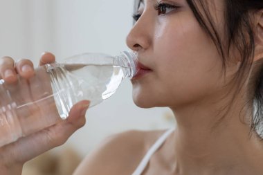 Spor yaparken su şişesinden su içen Asyalı genç bayan sporcu. Her gün susuz kalma. Sağlıklı, sağlıklı, sağlıklı, sağlıklı bir kadın. Su içmek iyi hissettirir..