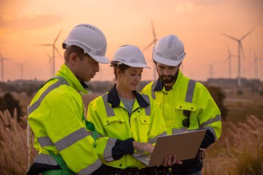 Dizüstü bilgisayarı tutan güvenlik üniforması giyen takım mühendisi akşam güneş battığında enerji santralinde yenilenebilir enerji planlarını tartıştı. Teknoloji ortamı küresel ısınma sorunlarını azaltıyor.