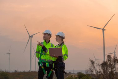 Dizüstü bilgisayarı tutan güvenlik üniforması giyen takım mühendisi akşam güneş battığında enerji santralinde yenilenebilir enerji planlarını tartıştı. Teknoloji ortamı küresel ısınma sorunlarını azaltıyor.