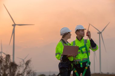 Dizüstü bilgisayarı tutan güvenlik üniforması giyen takım mühendisi akşam güneş battığında enerji santralinde yenilenebilir enerji planlarını tartıştı. Teknoloji ortamı küresel ısınma sorunlarını azaltıyor.