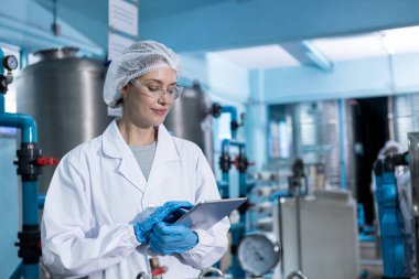 Kadın işçi QC tablet üretim hattını kullanarak yüksek basınçlı içme suyu filtresi ile suyu plastik şişelere doldurarak tüketicilere sunuyor. Fabrikada su var..