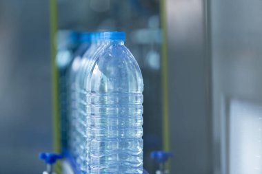 Su içme tesisi. Fabrika üretim hattında seçici odaklı su şişeleri. Suyun plastik şişelere doldurulup tüketicilere sunulması süreci