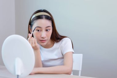 Güzel bir kadın aynaya bakar ve makyaj yapar..