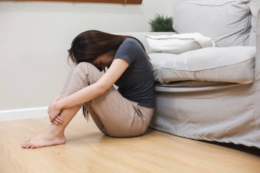 Oturma odasında depresyonda olan bir kadın. Depresif kucaklayıcı dizler. mutsuz duygu.