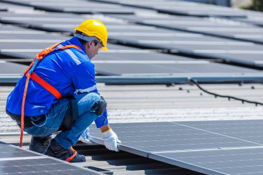 Teknisyenler, bir sanayi fabrikasının çatısına güneş paneli standartları kurup denetliyorlar. Doğadan elde edilen elektrik enerjisi güneş ışığı temiz yenilenebilir enerji.