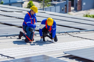 Mühendis, güneş panellerinin standartlarını endüstriyel bir fabrikanın çatısına kurup teftiş etti. Ekip teknisyeni güneş pilini kontrol edip tamir ediyor. Alternatif yenilikçi güç çevresi.