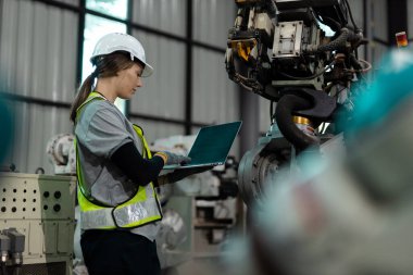 Otomatik mühendis kadın otomatik tamirci otomasyon robotlarının kalite kontrol sistemini kullanarak fabrikada çalışıyor. Fabrikada üretim yapan servis programlama makineleri..