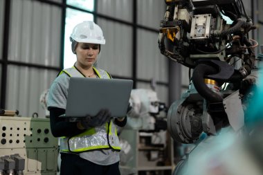 Otomatik mühendis kadın otomatik tamirci otomasyon robotlarının kalite kontrol sistemini kullanarak fabrikada çalışıyor. Fabrikada üretim yapan servis programlama makineleri..