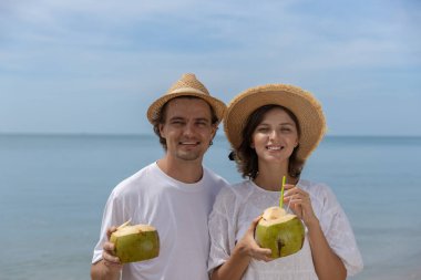 Mutlu rahatlatıcı çift, yaz tatilinde sahilde hindistan cevizi suyu içer. Tatilde birlikte seyahat etmek..