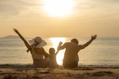 Aile, kumsalda mutlu bir şekilde dinleniyor çocuklar. Anne baba, yaz tatilinde birlikte seyahat ediyor. Tropikal gün batımı zamanı. Trip bağlanmanın tadını çıkarıyor. Aile günü eğleniyor..