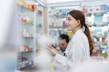 Çalışan kadın eczacılar eczanedeki raflarda bulunan seçkin ilaçlardır. Eczanedeki ürünlerin bilgi çeşitliliği için uyuşturucu satıcısı ilaç kontrolü.