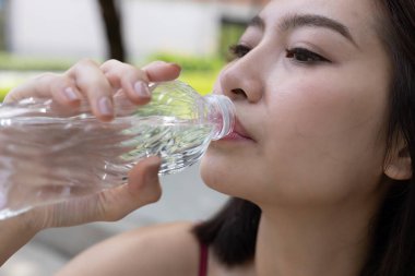 Spor yaparken su şişesinden su içen Asyalı genç bayan sporcu. Her gün susuz kalma. Sağlıklı, sağlıklı, sağlıklı, sağlıklı bir kadın. Su içmek iyi hissettirir..