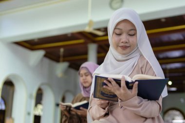 Camide Kur 'an okuyan tesettürlü güzel Müslüman kadınlar. İslami kadın tanrıya dua. Ramazan ve bayram fastikal kavramı.