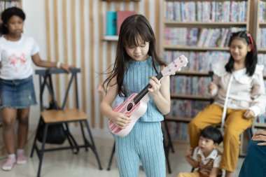 Sınıfta ukulele çalma pratiği yapan okul çocukları eğitimi. Liseli kız mutlu öğrenmeler. Öğretmenin öğrettiği gibi yazıyorum. Okula dönüş konsepti.