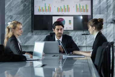 Konferans odasında veri analizi yapan ve stratejiler hazırlayan iş adamları, proje stratejileri ve iş stratejileri tartışılırken ekranda gösterilen tablo ve grafiklerin incelenmesi,.