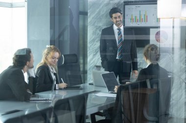 Ekip üyeleri parlak ofis alanlarında işbirliği yaparak veri ve proje stratejilerini tartışırken, lider ekranda içgörüler sunuyor, yenilikleri teşvik ediyor ve takım çalışmasını destekliyor.