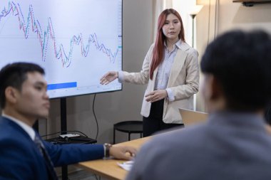 Çağdaş ofis ortamında mali raporları ve çizelgeleri tartışan bir grup profesyonel iş toplantısına katıldı. İstatistik ve şirket büyüme grafiklerinin beyin fırtınası ve analizi