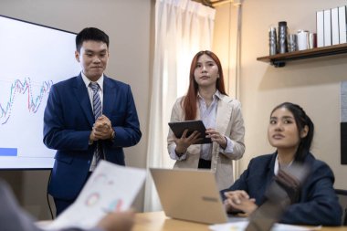 Çağdaş ofis ortamında mali raporları ve çizelgeleri tartışan bir grup profesyonel iş toplantısına katıldı. İstatistik ve şirket büyüme grafiklerinin beyin fırtınası ve analizi