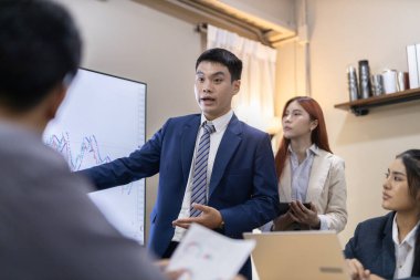 Çağdaş ofis ortamında mali raporları ve çizelgeleri tartışan bir grup profesyonel iş toplantısına katıldı. İstatistik ve şirket büyüme grafiklerinin beyin fırtınası ve analizi