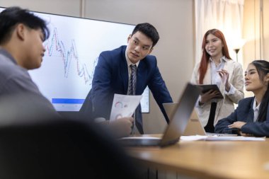 Çağdaş ofis ortamında mali raporları ve çizelgeleri tartışan bir grup profesyonel iş toplantısına katıldı. İstatistik ve şirket büyüme grafiklerinin beyin fırtınası ve analizi