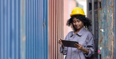 Üniformalı gülümseyen Afrika kökenli Amerikalı kadın, elinde tablet bulunan sert şapka kapları takıyor. Alan lojistik ihracat ve nakliye.