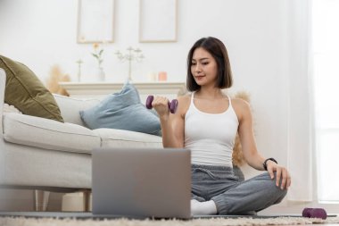 Genç bir bayan omuz çalışıyor. Kol egzersizi yapıyor. Çevrimiçi egzersiz yapıyor..