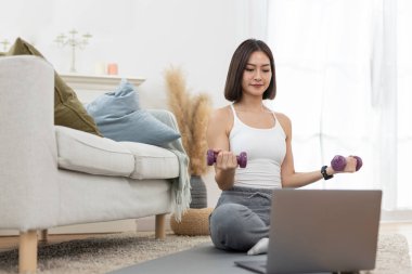 Genç bir bayan omuz çalışıyor. Kol egzersizi yapıyor. Çevrimiçi egzersiz yapıyor..