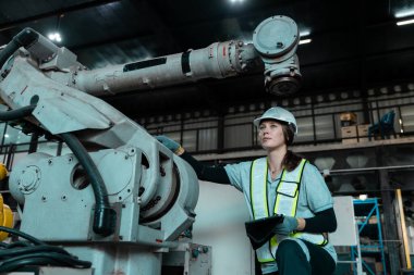 Otomatik mühendis kadın otomatik tamirci otomasyon robotlarının kalite kontrol sistemini kullanarak fabrikada çalışıyor. Fabrikada üretim yapan servis programlama makineleri..