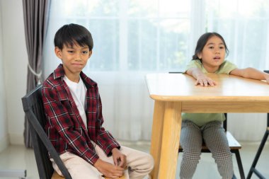 İki çocuk parlak bir odada ahşap bir masada oturuyorlar. Bir çocuk dikkatle dinlerken, diğeri coşkuyla bir fikri dile getiriyor, canlı bir atmosfer yaratıyor..