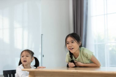 Çocuklar büyük pencereli, parlak ve neşeli bir ortamda kapalı alanlarda oyun oynarken eğleniyorlar.