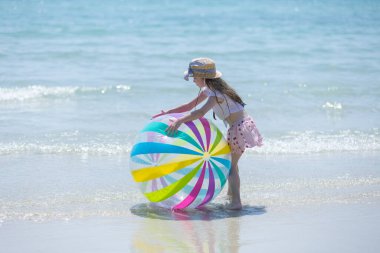 Küçük kız güneşli bir günü gündüz vakti top oynayarak, mutlu çocuklar denizde oynayarak, sınıf dışında öğrenerek geçirir. Parlayan su komik atmosferi över..